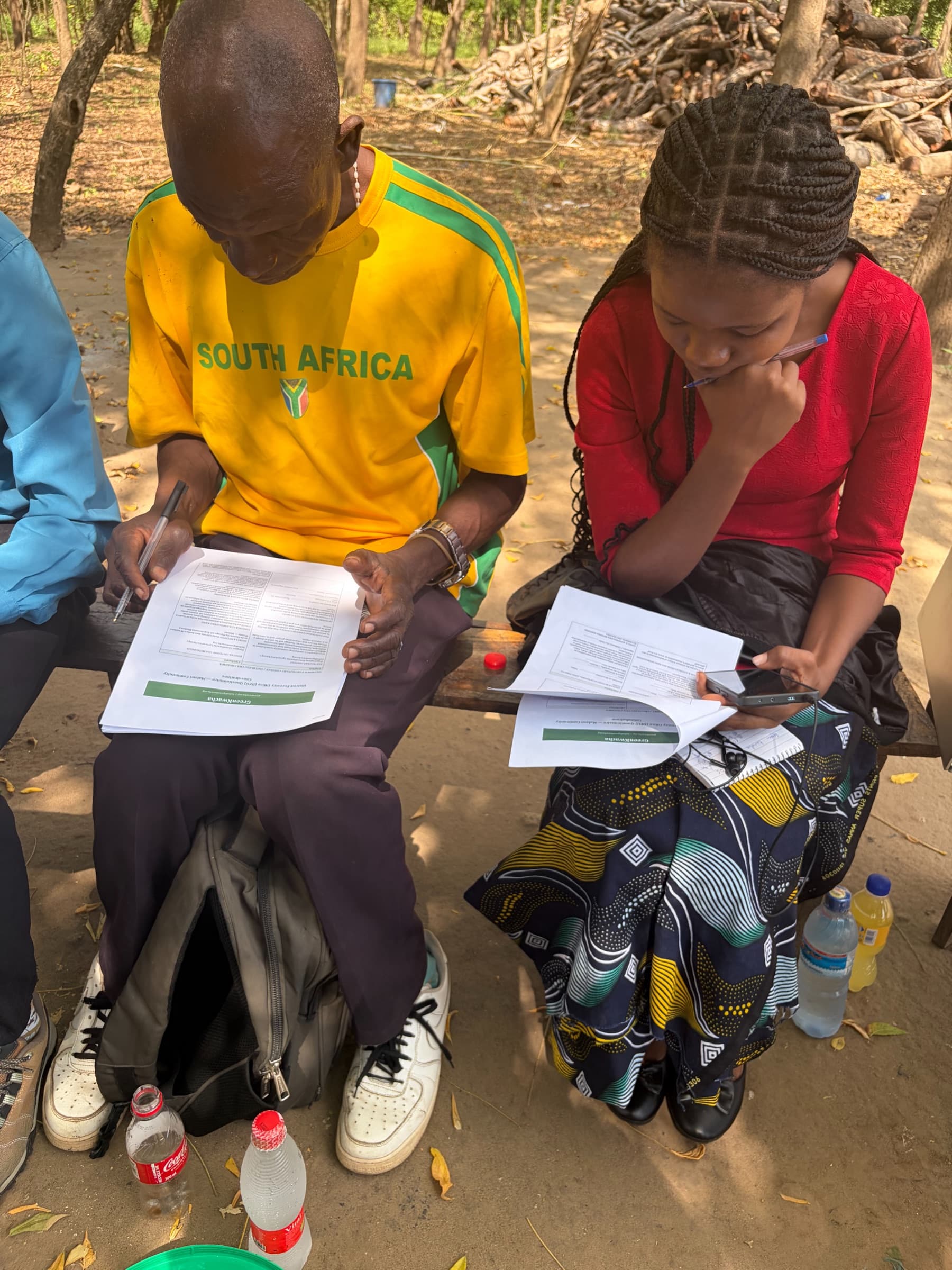 Community members filling in the GreenKwacha consultation questionnaire by hand in the Lower Shire.